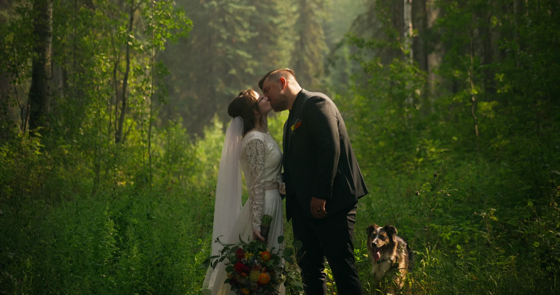 A couple sharing a kiss in a sunlit forest, filmed by Evergreen Films